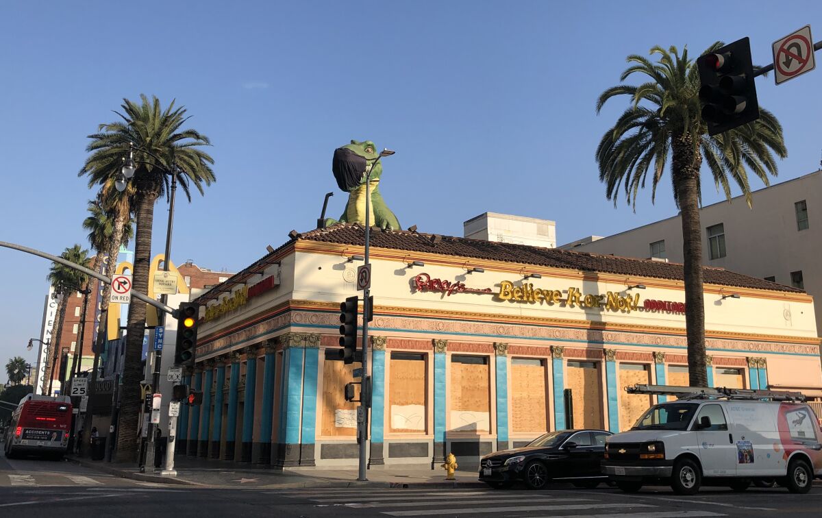 A mask-wearing T-Rex stands over the boarded up Ripley's Believe It or Not Museum in Hollywood.