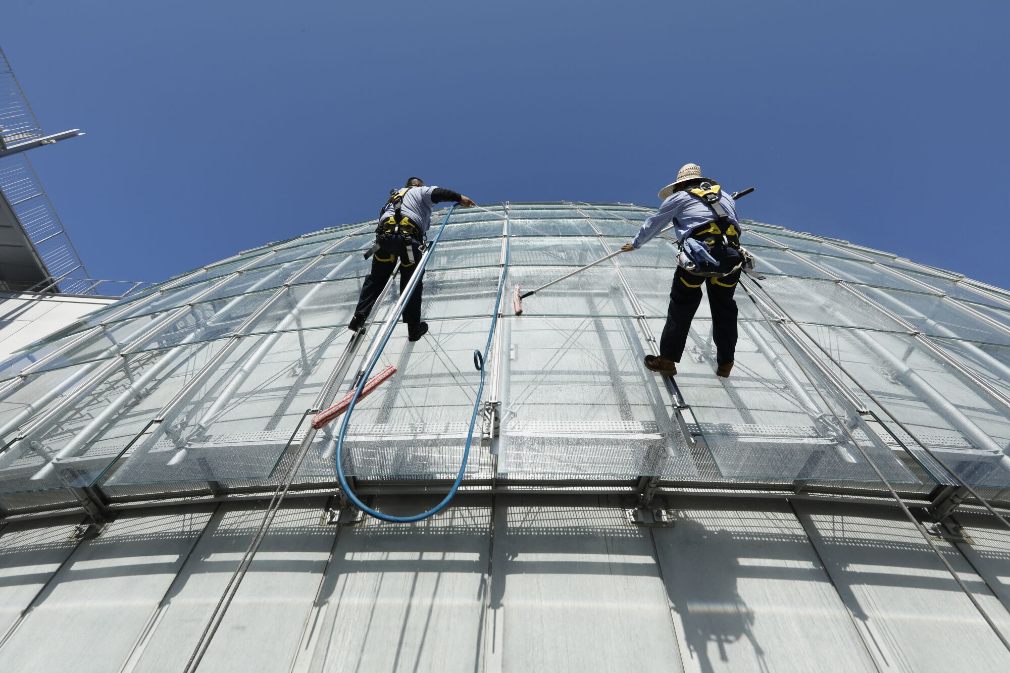  Mario Guzman and Jesus Garcia clean the windows on the giant glass dome of the Academy Museum of Motion Pictures. 