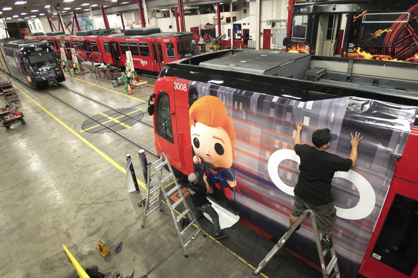 David Garcia, right, and Anthony Soltero put on a section of transit vinyl as they and a crew put on an advertising wrap for TBS television host Conan O'Brien's talk show on a trolley car.