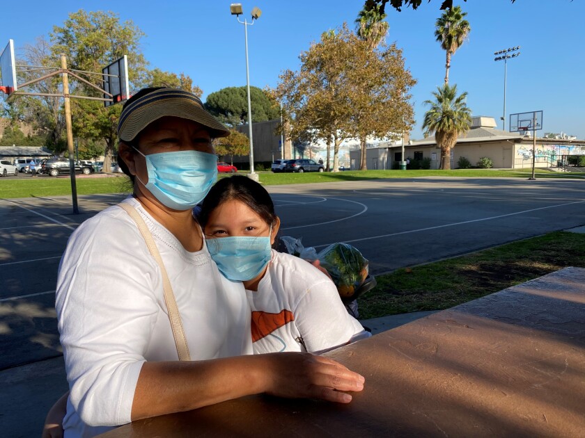 Melba Martinez pulls daughter Daniela in close as they sit at a picnic table.