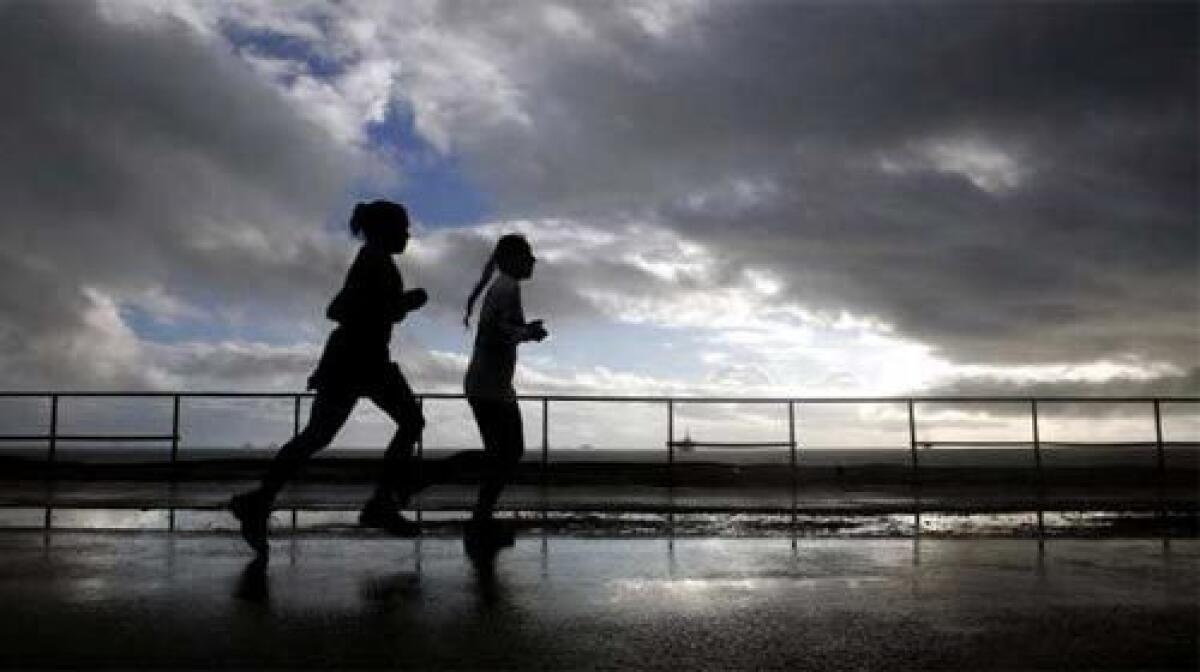 BETWEEN THE RAINDROPS: A jog at Huntington City Beach comes between the late-weekend storm and an expected deluge.