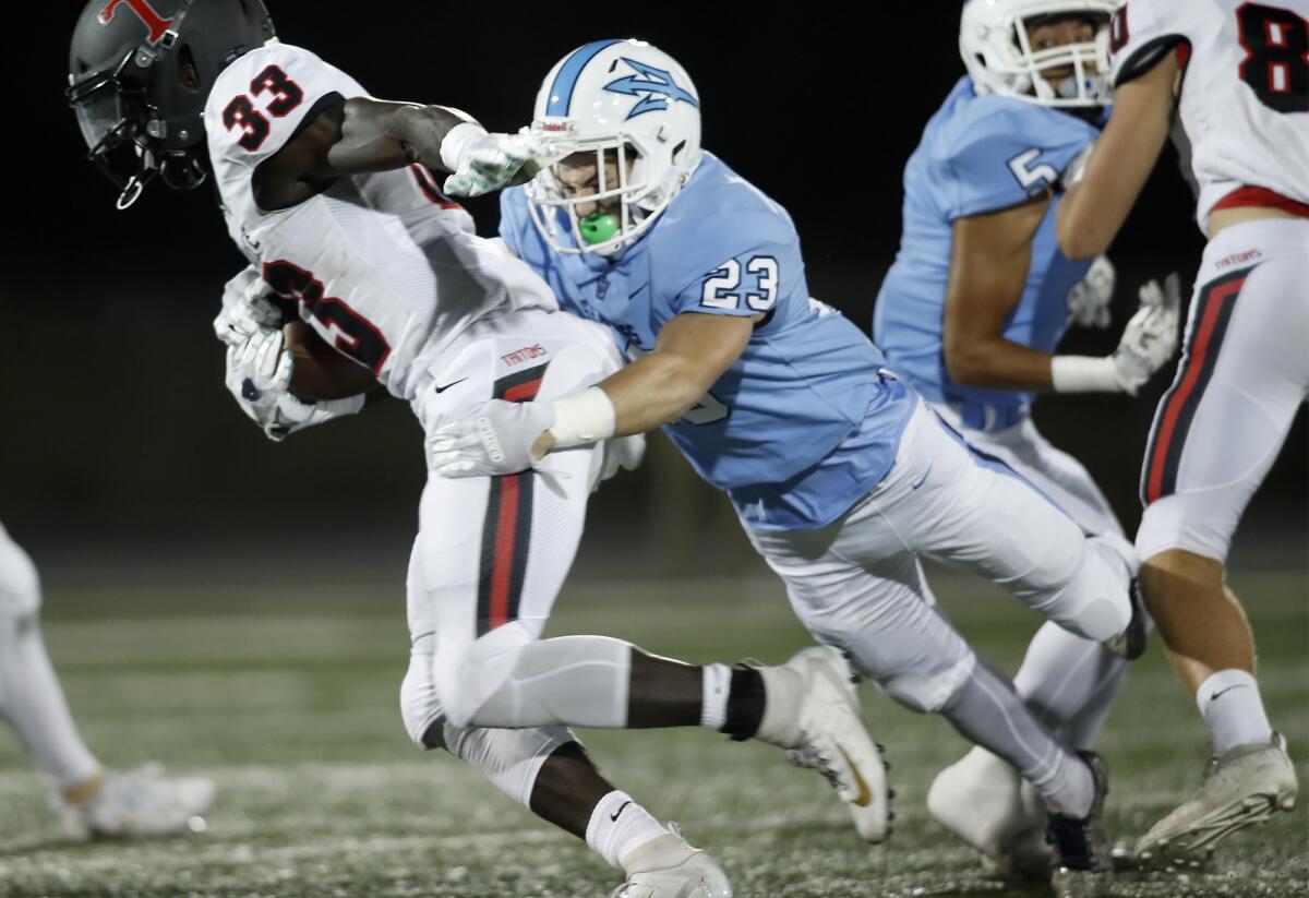 Corona del Mar's Zack Green (23) forces San Clemente's James Bohls to fumble during the first quarter at Newport Harbor High on Thursday. Green recovered the fumble.