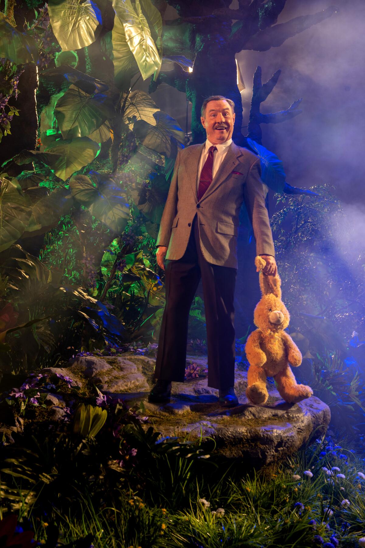 An image of a man in a suit holding a stuffed animal.