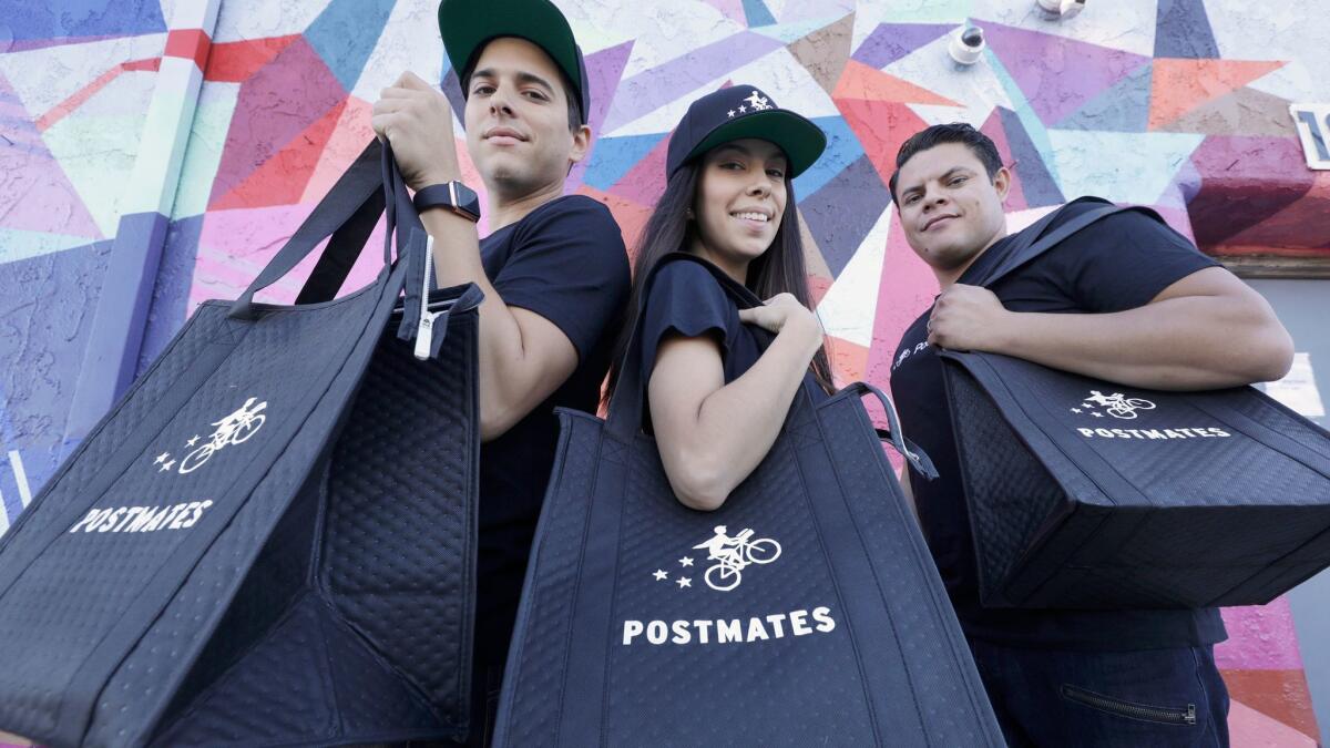 Postmates couriers Gus Peroba, left, Demiries Mendez and Gabriel Figueroa outside a commissary kitchen for Tatsu Ramen near downtown L.A. that prepares ramen orders to go.