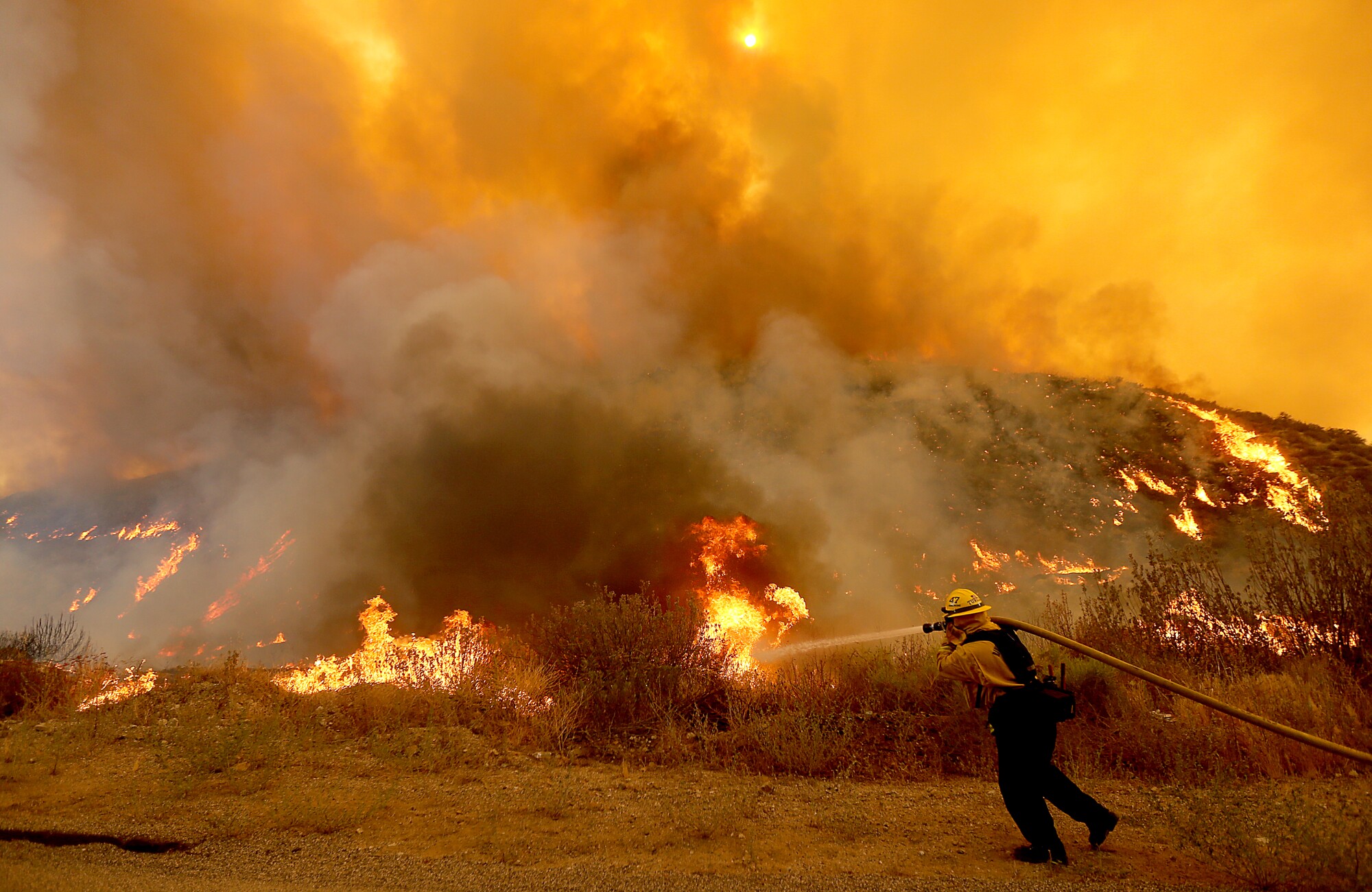 A firefighter battles the Fairview fire along Batista Road near Hemet