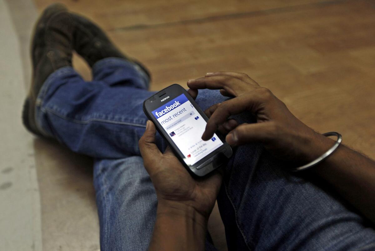 In this 2012 file photo, a man surfs the Facebook site on his mobile phone in Mumbai, India.