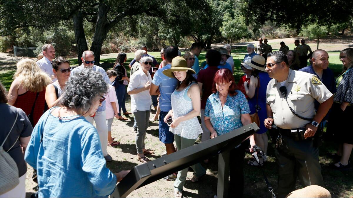Attendees look at the new sign after the unveiling Friday in the western section of Crescenta Valley Park. (Raul Roa / Glendale News-Press)