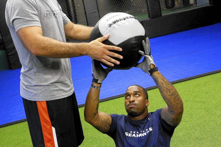 Jeron Johnson, an NFL player with the Seattle Seahawks, works with a trainer as he does sit-ups with a medicine ball at Unbreakable Performance Center off the Sunset Strip.