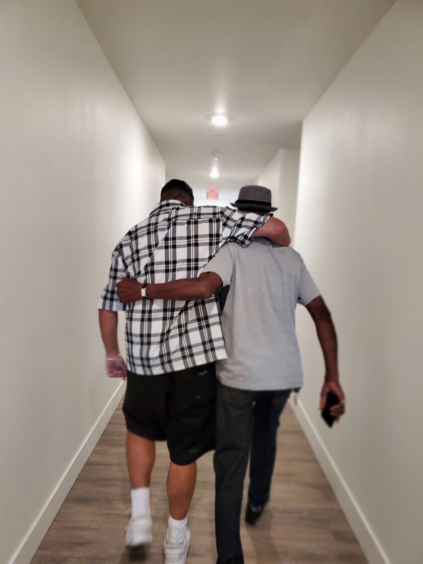 Two formerly homeless veterans walk in the hallway at Jamboree's Heroes Landing in Santa Ana.