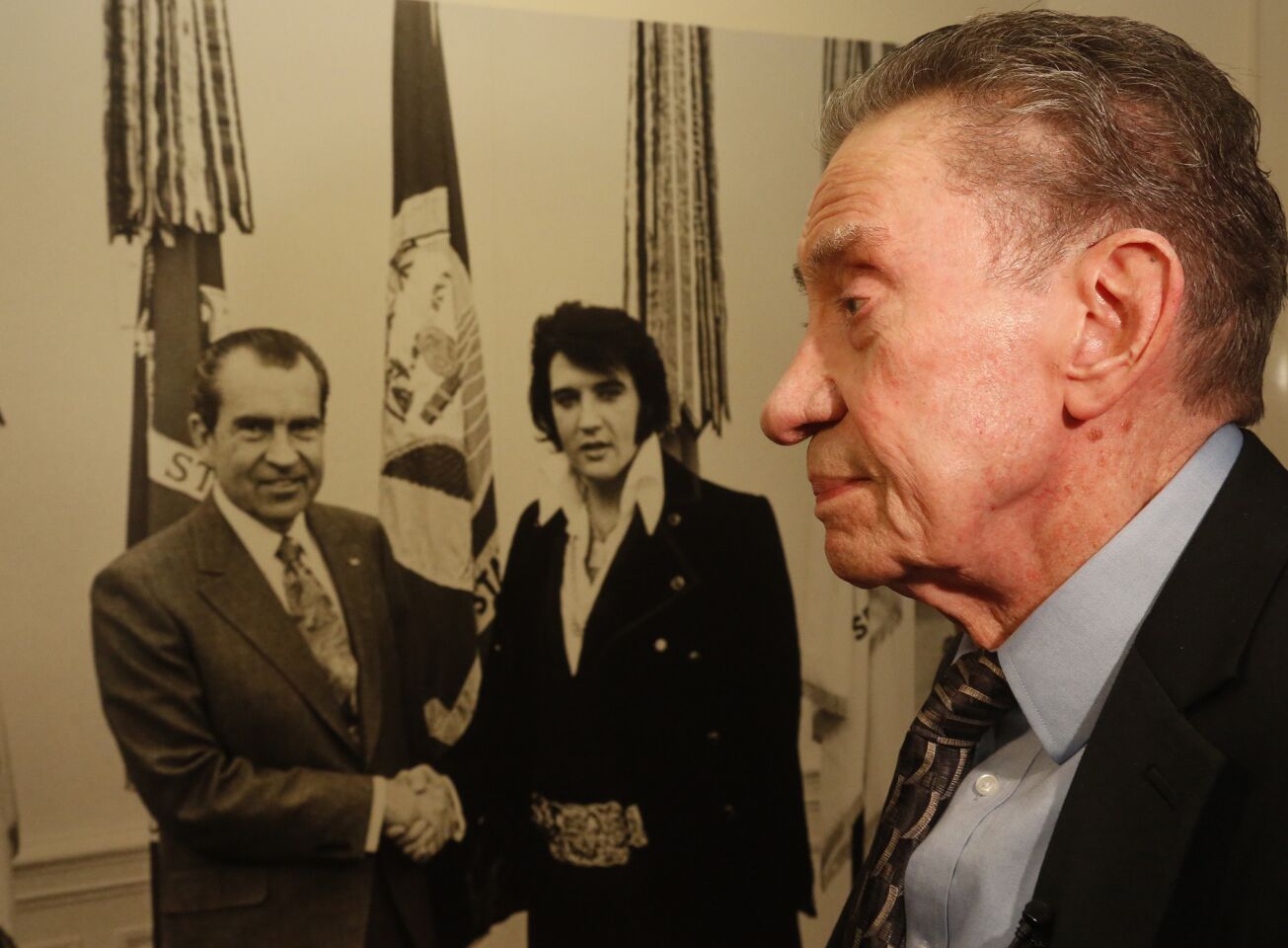 Richard Nixon's brother, Ed Nixon, walks past a photo of the president with Elvis Presley at the White House in 1970 during the reopening of the Nixon library in Yorba Linda.