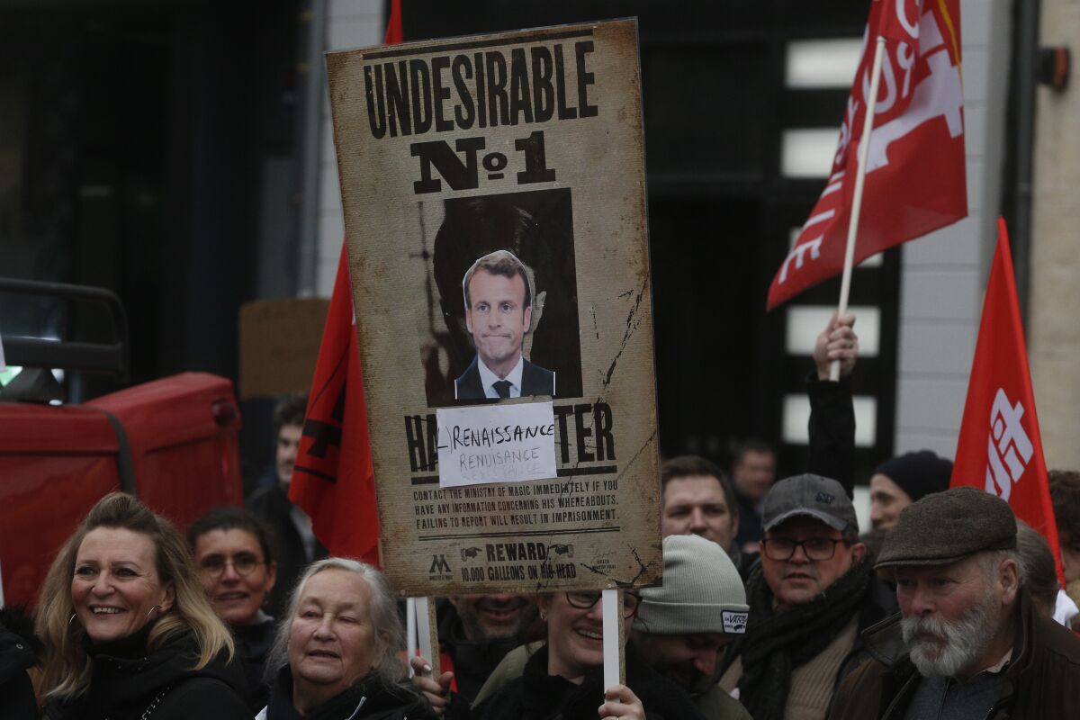 Protesters hold a placard with a portrait of Emmanuel Macron during a demonstration 