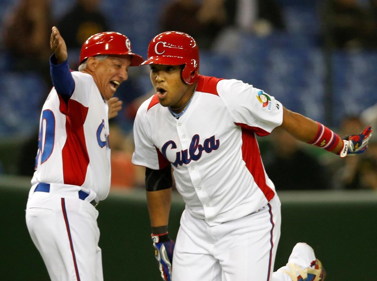 Cuba's rightfielder Yasmany Tomas, right, celebrates with third base coach Primitivo Diaz after hitting a three-run homer off Taiwan's pitcher Yang Yao-hsun in the fourth inning of their World Baseball Classic second round game at Tokyo Dome in Tokyo, Saturday, March 9, 2013.