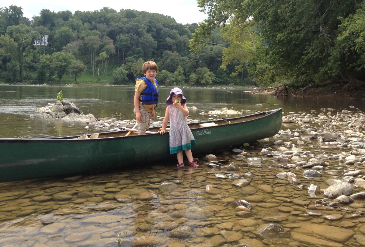 Two young children stand by a canoe during a break along the Potomac River.