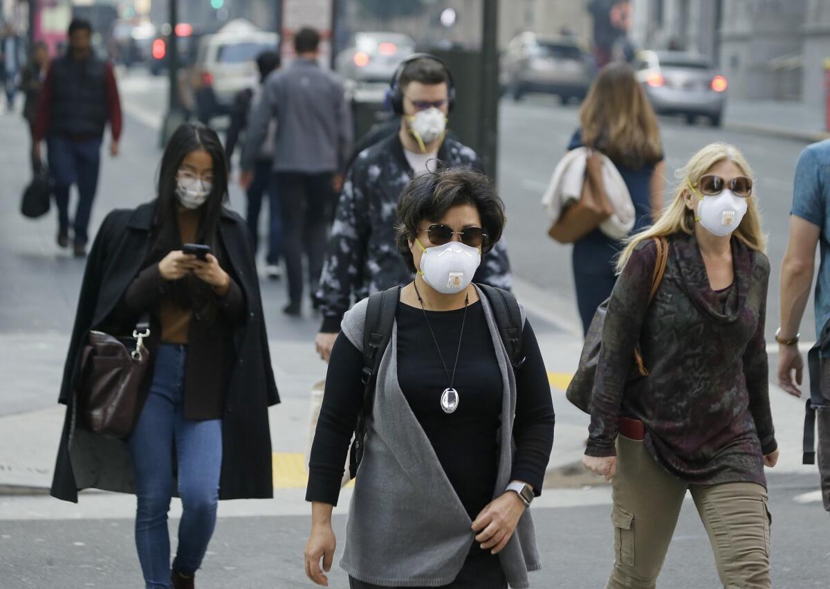 People wear masks while walking through the Financial District in the smoke-filled air in San Francisco.