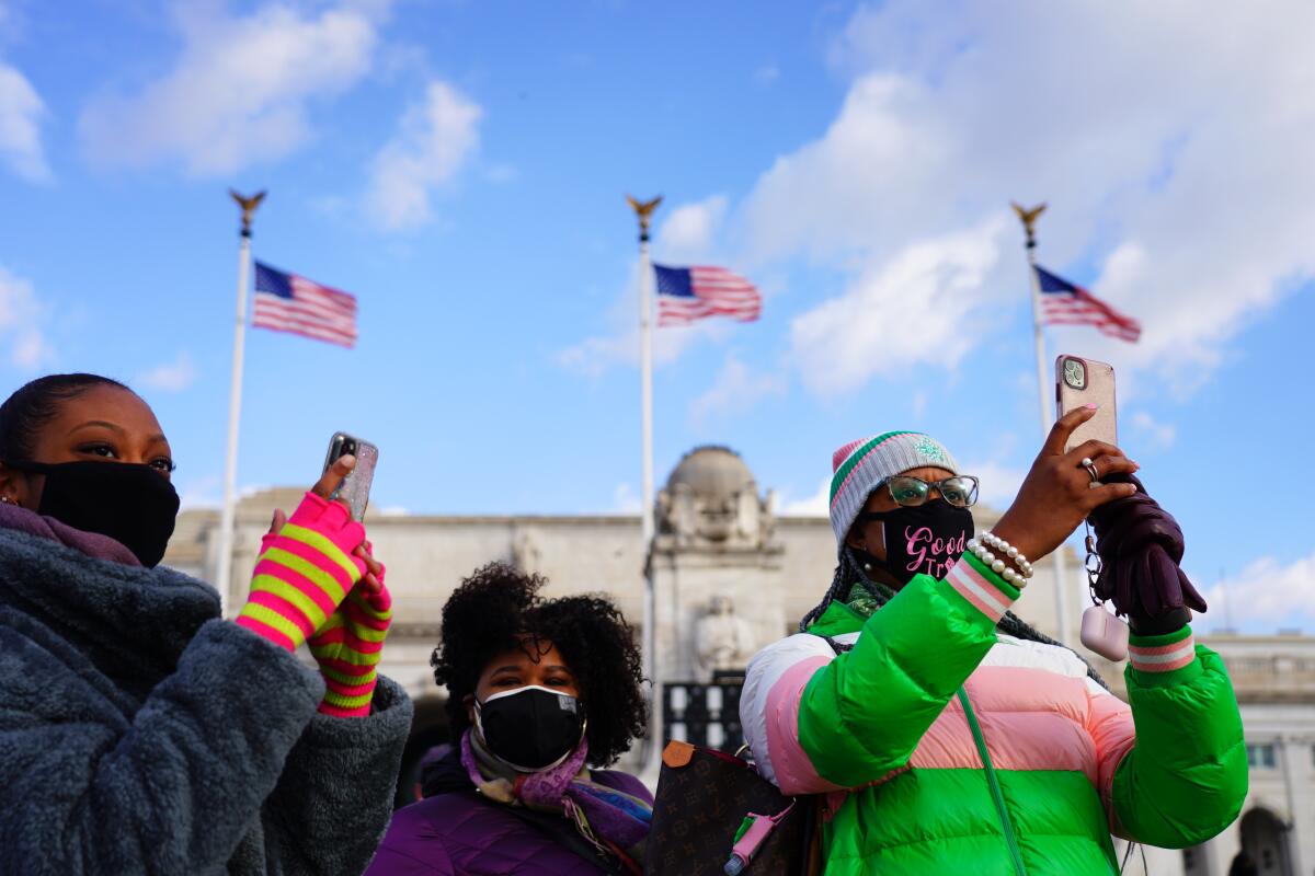 People hold up cellphones to film the post-inauguration motorcade.