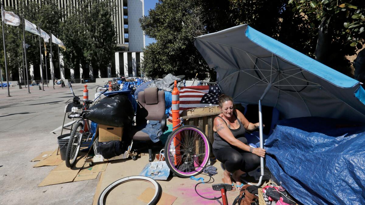 Homeless for several months now, Marnie Alcaraz finds a little shade under an umbrella at her encampment in the shadow of the Orange County Courthouse.