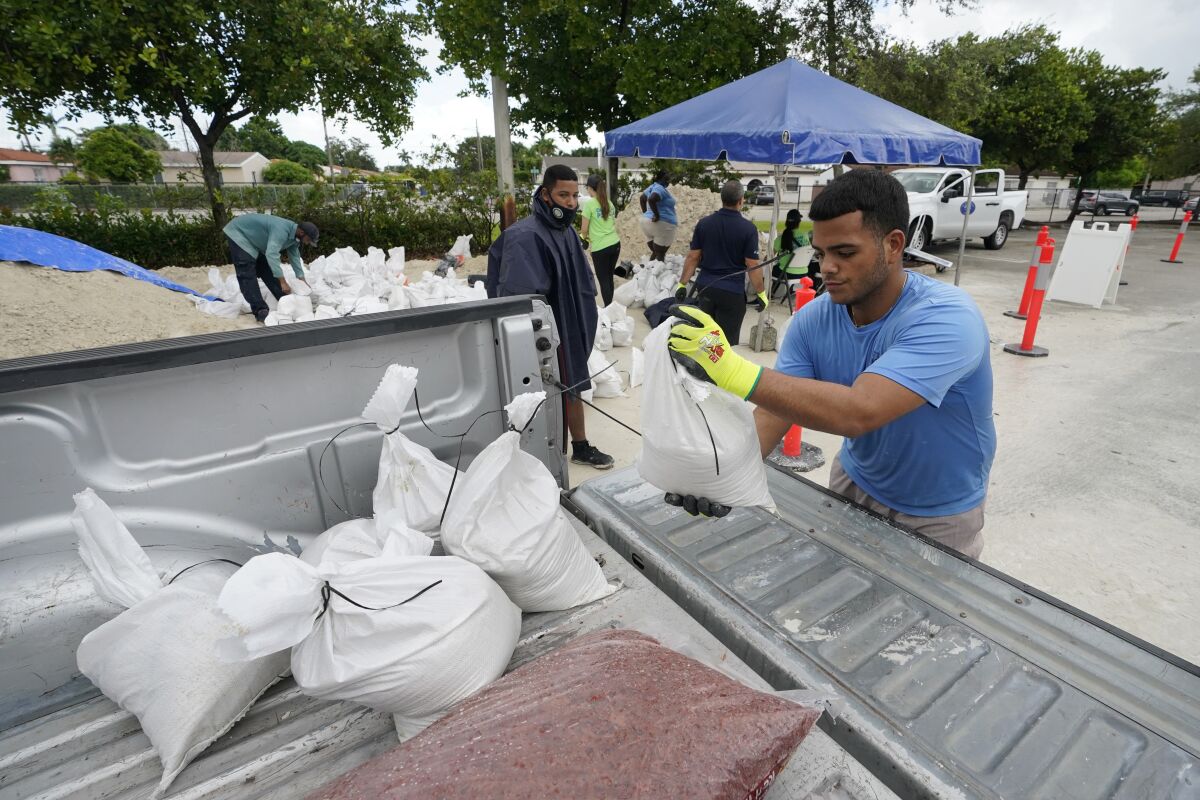 City workers load sandbags at a drive-thru sandbag distribution event for residents ahead of the arrival of rains associated with tropical depression Fred, Friday, Aug. 13, 2021, at Grapeland Park in Miami. Forecasters say tropical depression Fred is slowly strengthening and could regain tropical storm status Friday. (AP Photo/Wilfredo Lee)