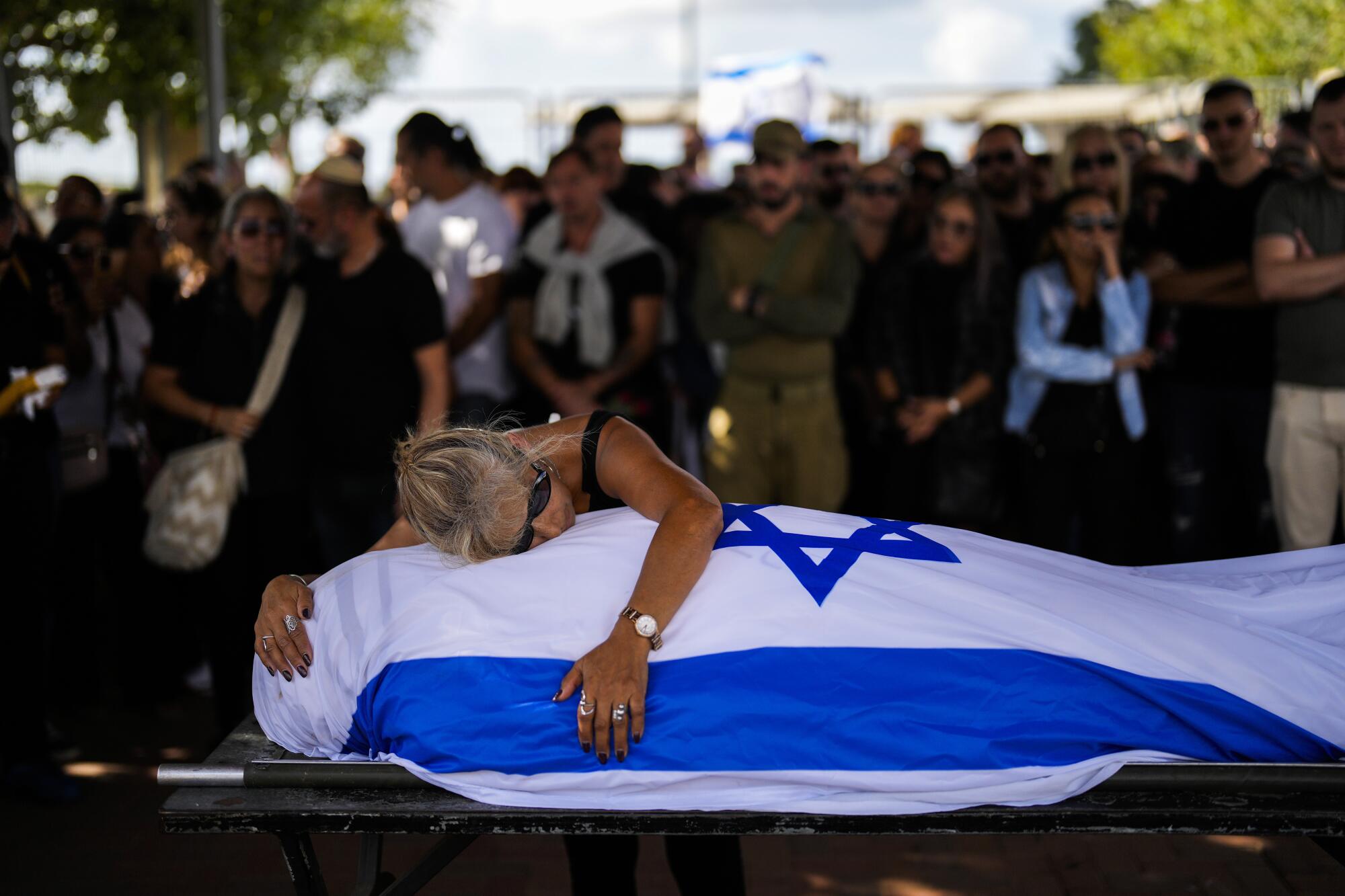 Woman crying over her son's body, which lies draped in the Israeli flag