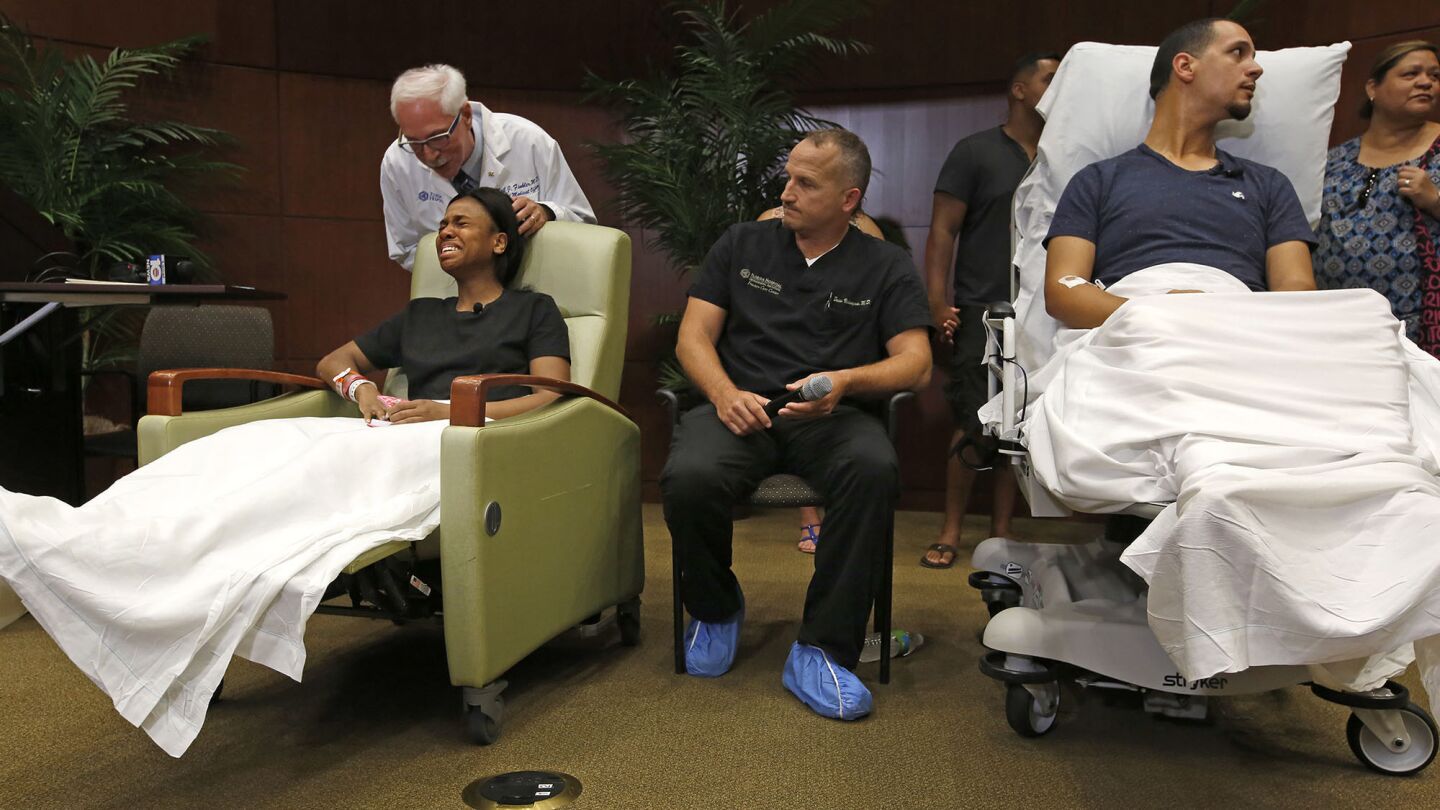 Gunshot victim Patience Carter, 20, left, is consoled by Dr. Neil Finkler at a news conference at Florida Hospital, joined by Dr. Brian Vickaryous, center, and fellow survivor Angel Santiago, 32, right, where they described the attack and its aftermath.