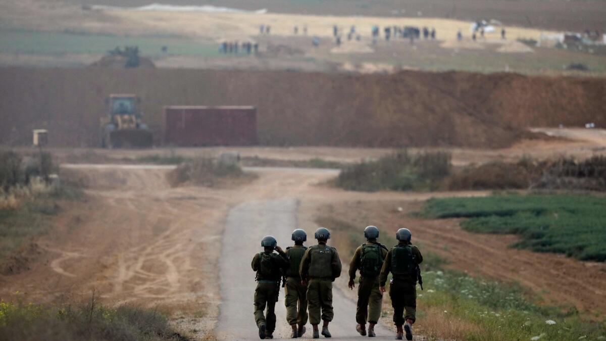 Israeli soldiers take up a position in front of Palestinian protesters on the Israeli-Gaza border near the town of Kfar Aza on April 24.
