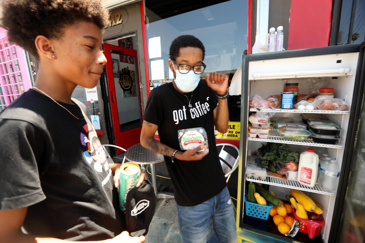  Joshua Mock, at right with son Nolan, owns Little Amsterdam coffee shop in Mid-City. The shop hosts a community fridge. 