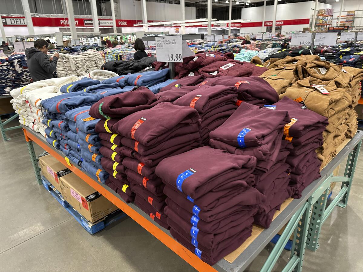 Shoppers look at stacks of hoodies in a Costco store.