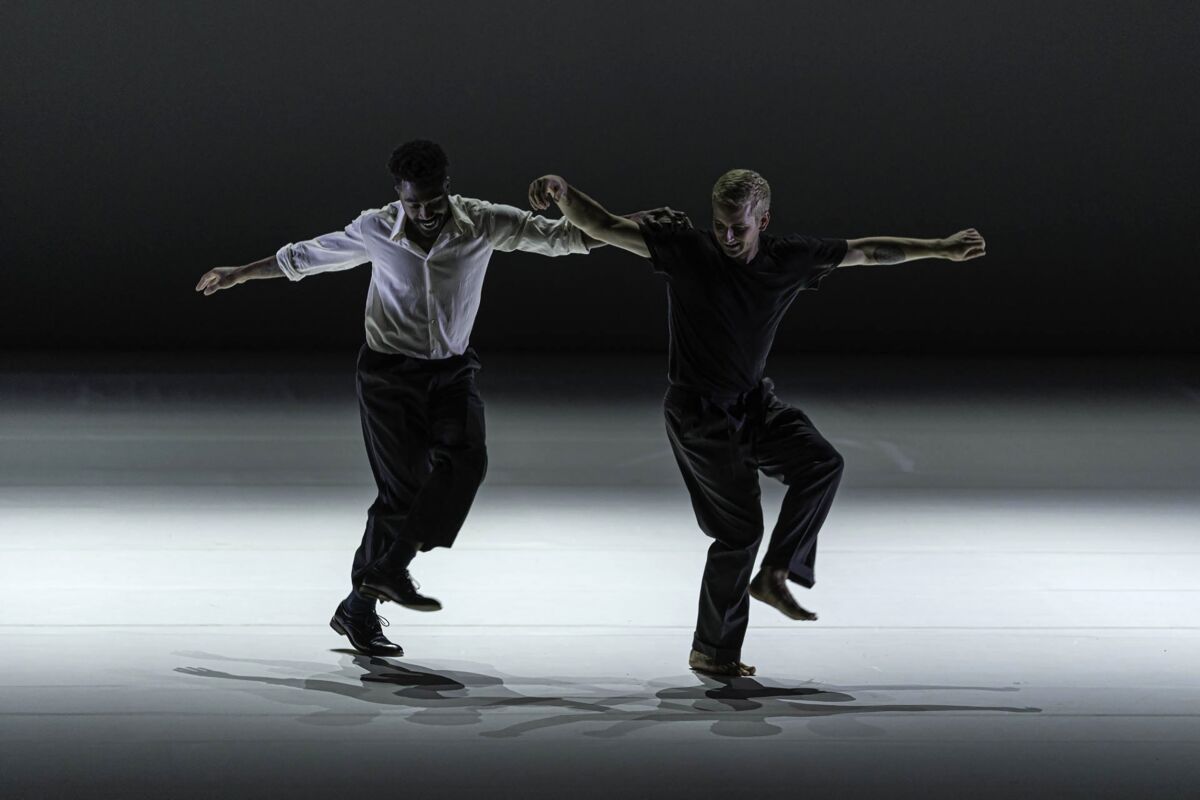 Two dancers move their arms and feet.