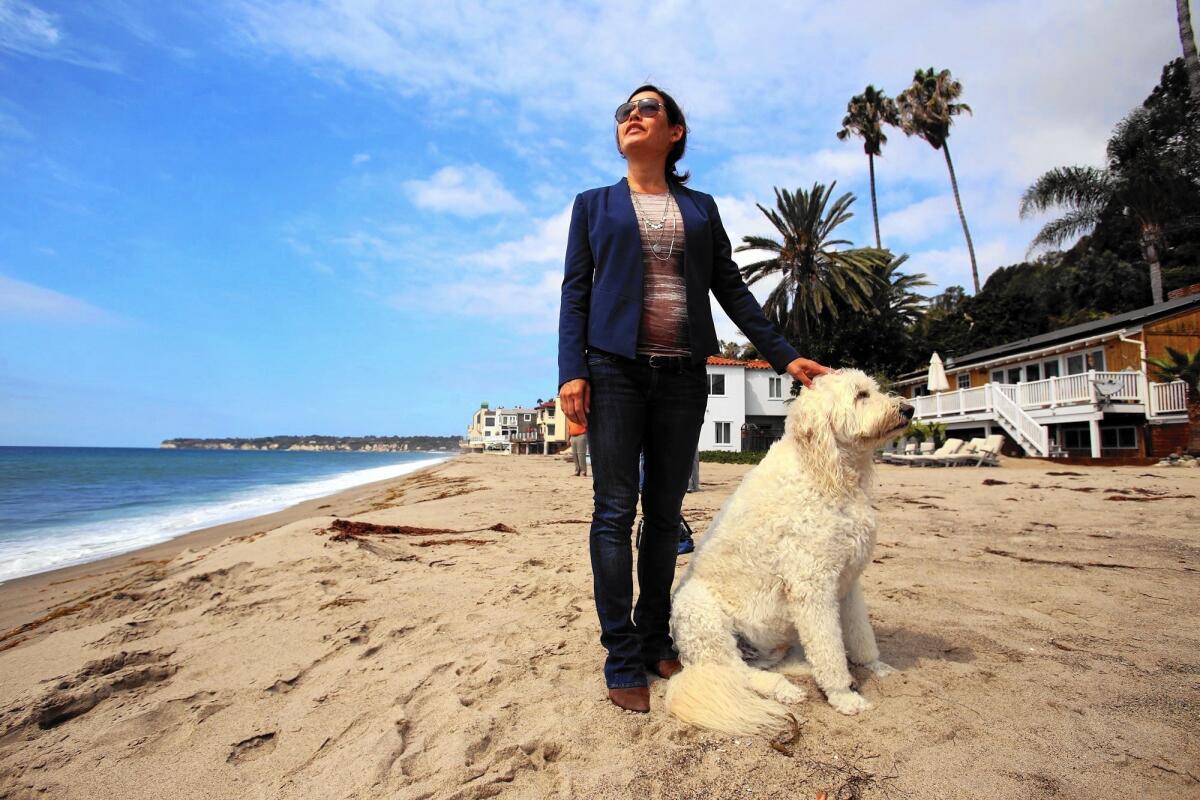 Noaki Schwartz, a spokeswoman for the California Coastal Commission, stands where a security guard asked her to leave because the beach is private -- it's not. She is photographed with a dog belonging to a local resident.