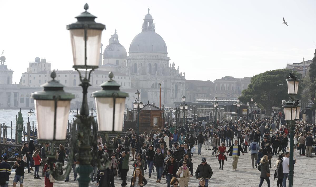 Large numbers of tourists stroll in downtown Venice, Italy.