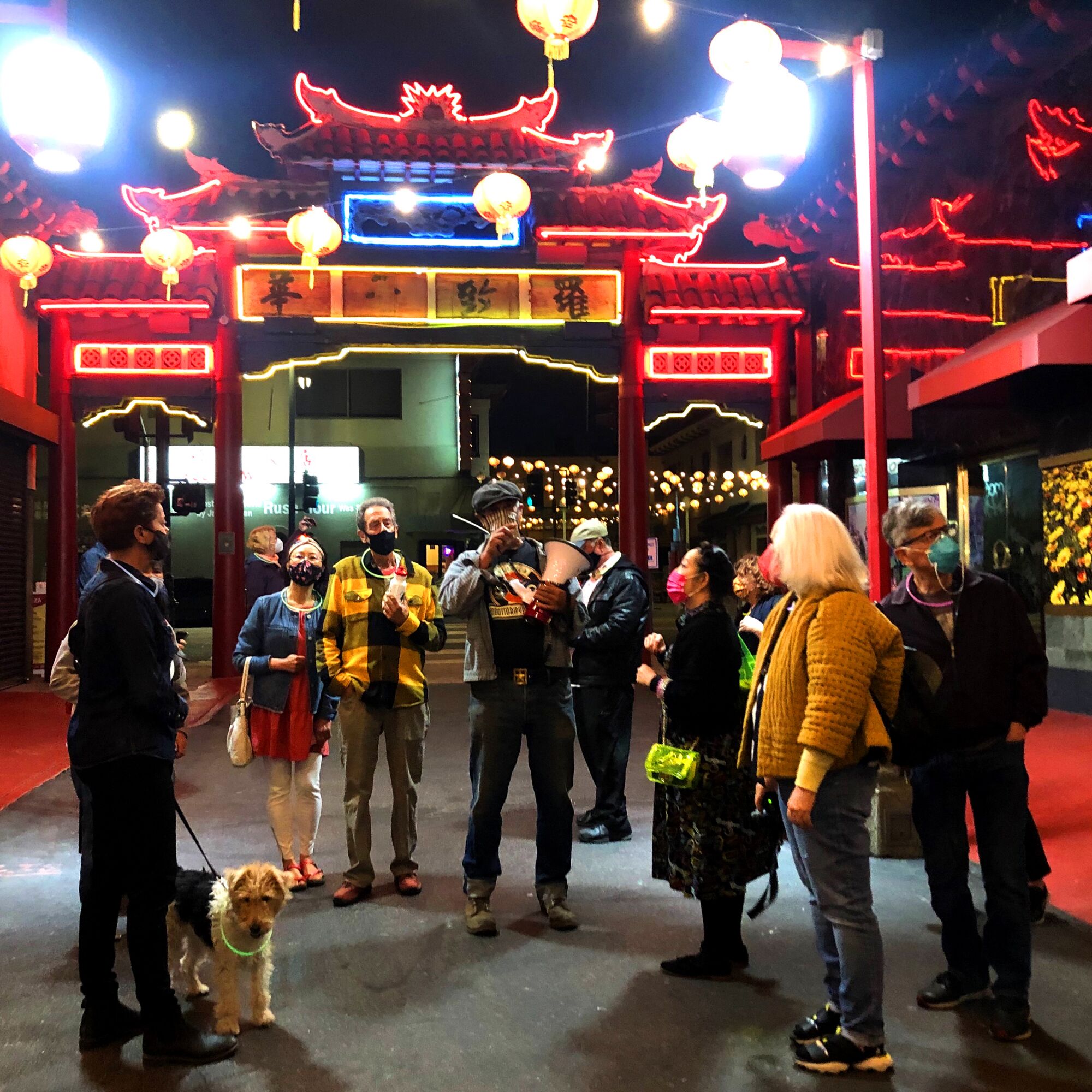 A gathering of people in Chinatown, lit up by neon lights.