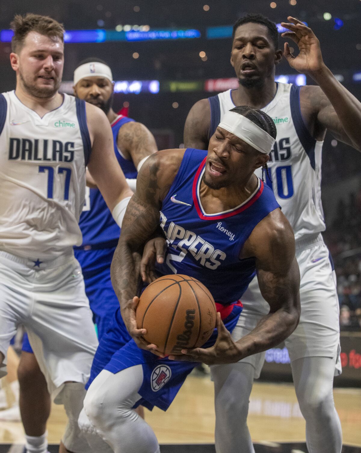 Clippers guard Eric Bledsoe grabs a rebound between Dallas Mavericks' Luka Doncic (77) and Dorian Finney-Smith.