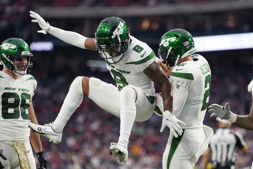 El quarterback de los Jets de Nueva York Zach Wilson (2) celebra su touchdown con Josh Johnson (8) ante los Texans de Houston, el domingo 28 de noviembre de 2021. (AP Foto/Eric Smith)