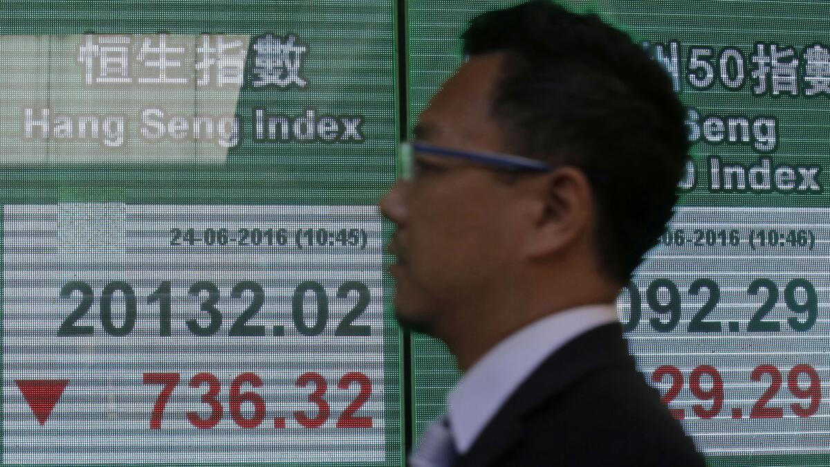A man passes a screen showing the Hang Seng index in Hong Kong on June 24.