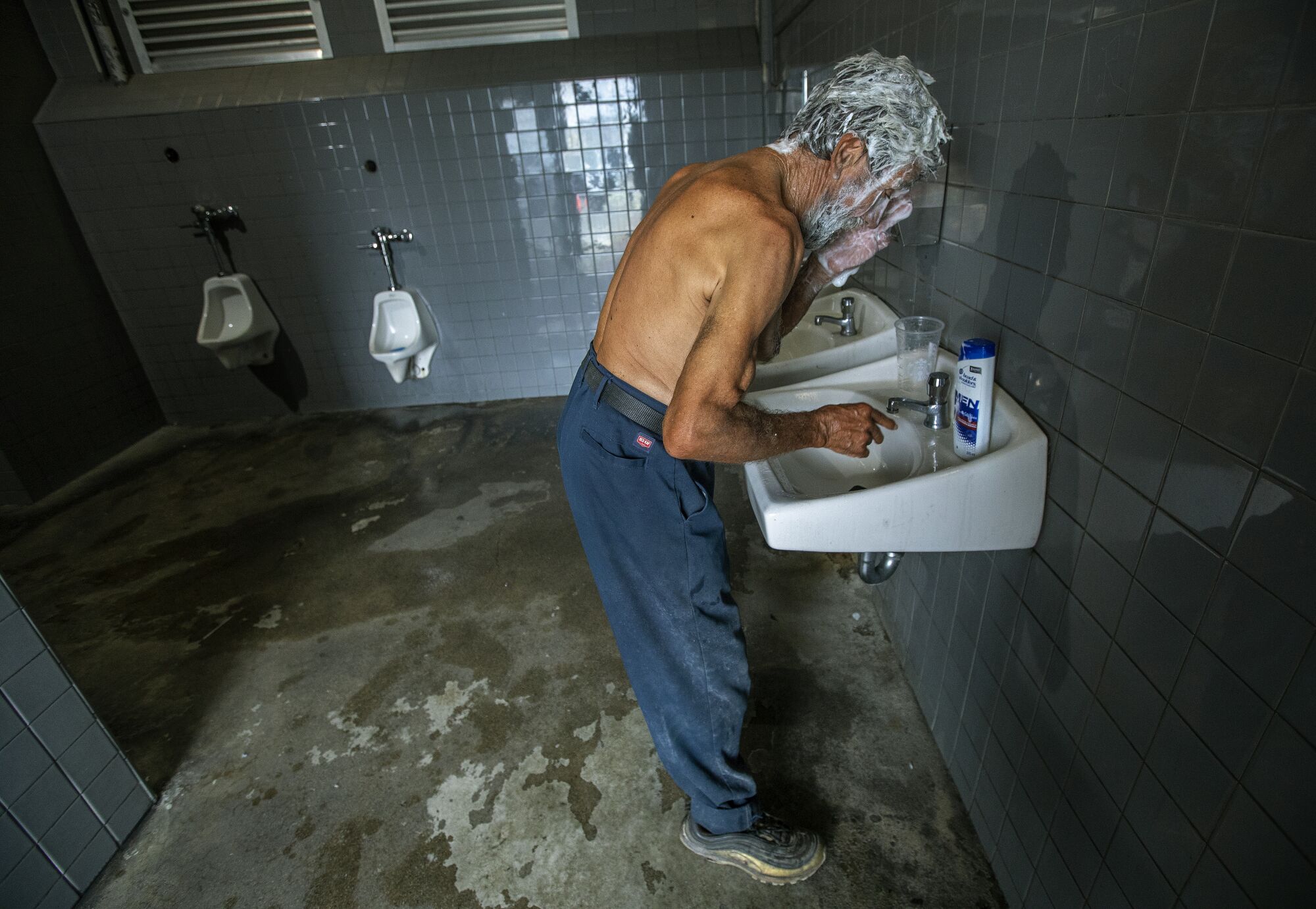 Augustine Hurtado washes his hair inside a restroom at Santa Monica State Beach.