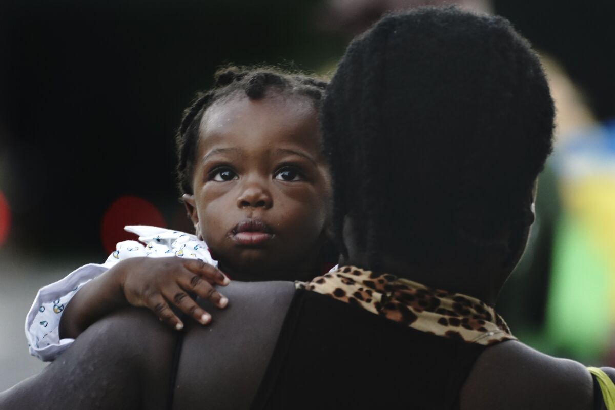 A Haitian migrant carrying a baby walks along the highway in Huixtla, Chiapas state, Mexico, early Thursday, Sept. 2, 2021, in their journey north toward the U.S. (AP Photo/Marco Ugarte)