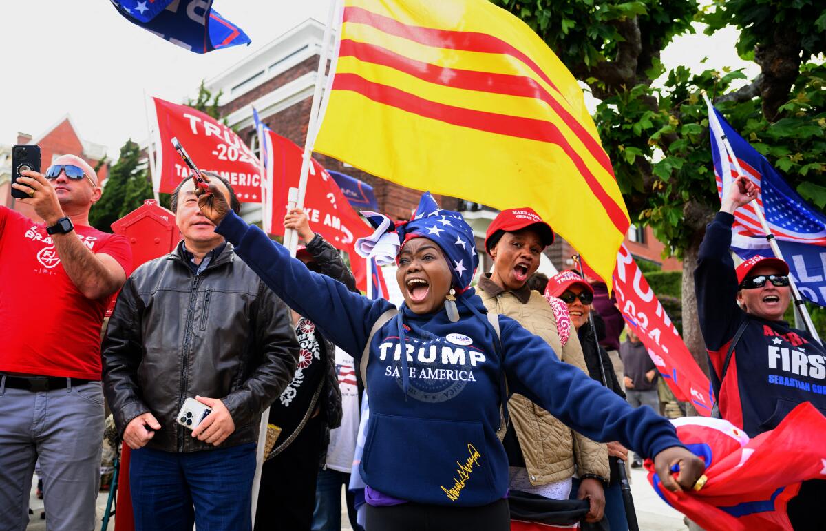 Supporters of former President Trump yell and wave flags at a rally