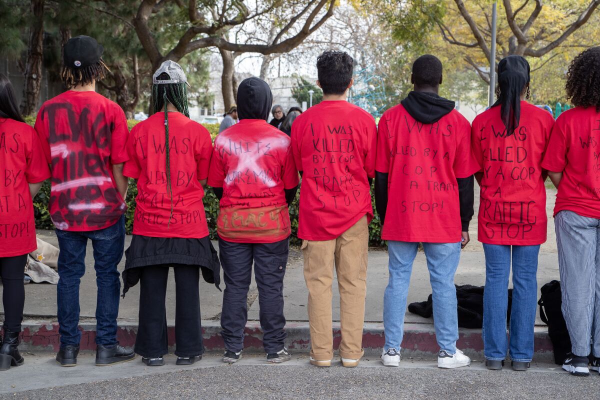 Protesters turn their backs at Frieze to display shirts that read "I was killed by a cop at a traffic stop." 