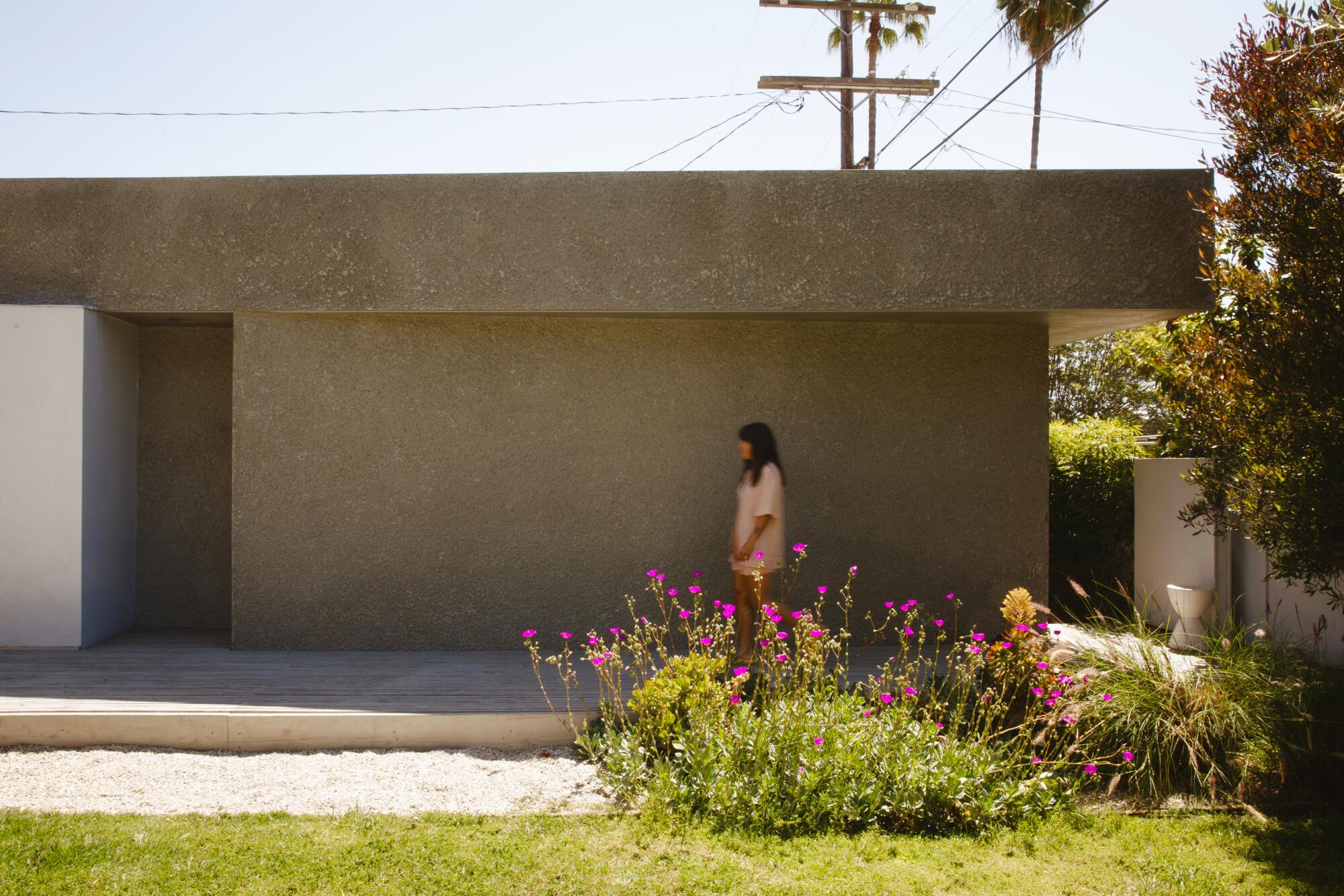 Catie Marques Teles walks outside he ADU facing her landlord's backyard 