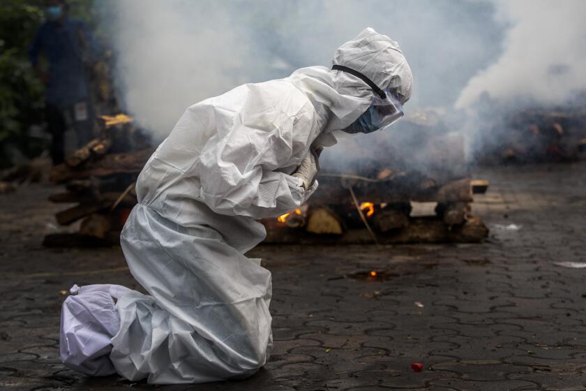 FILE - In this July 2, 2021, file photo, a woman breaks down as she prays before the cremation of a relative who died of COVID-19 in Gauhati, India. (AP Photo/Anupam Nath, File)