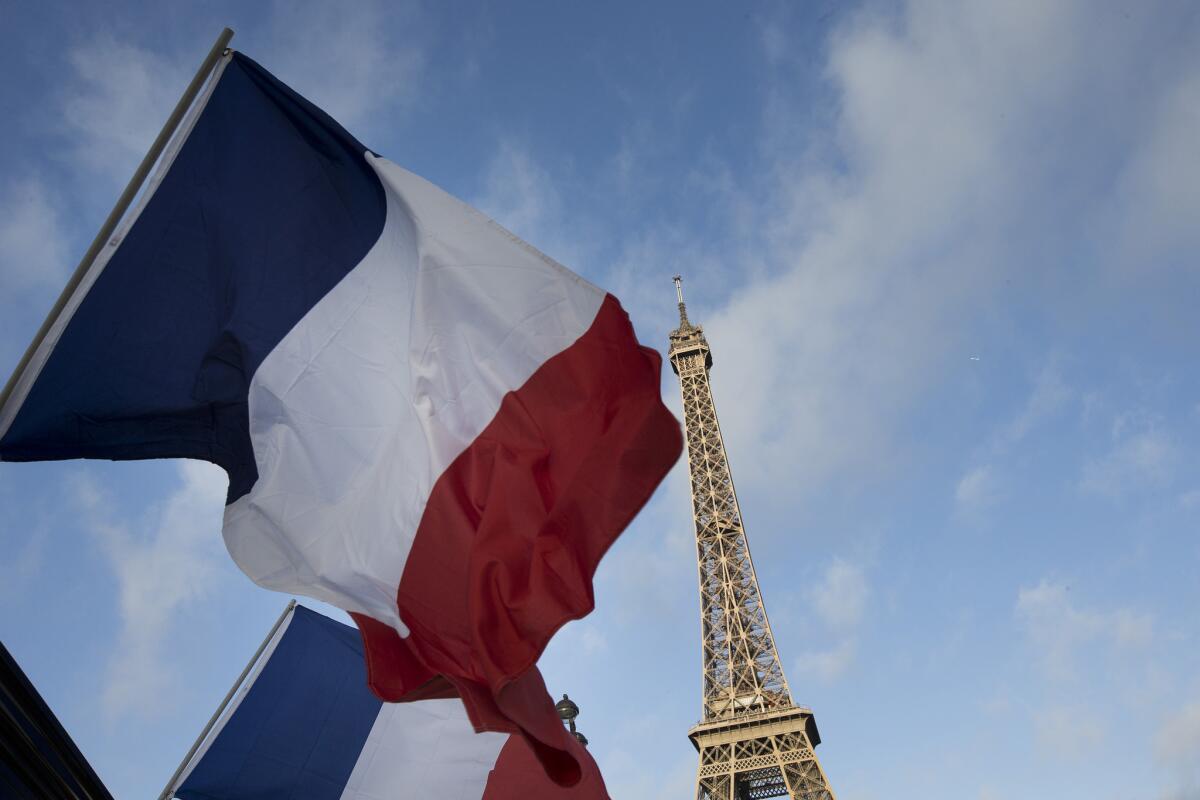 Dos banderas francesas ondean en los alrededores de la Torre Eiffel, cerrada en el primero de tres días de duelo nacional en París, el domingo 15 de noviembre de 2015.