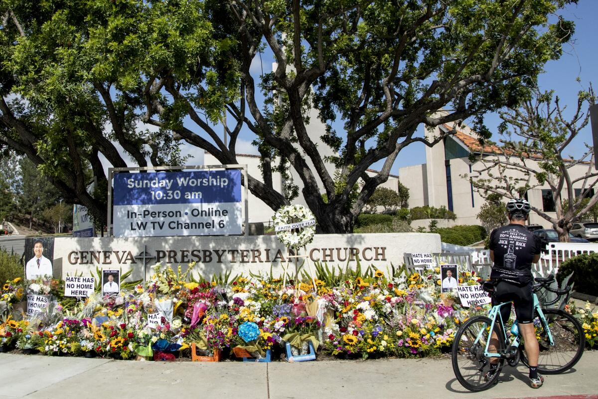 A bicyclist stops at a sidewalk memorial in front of a church.