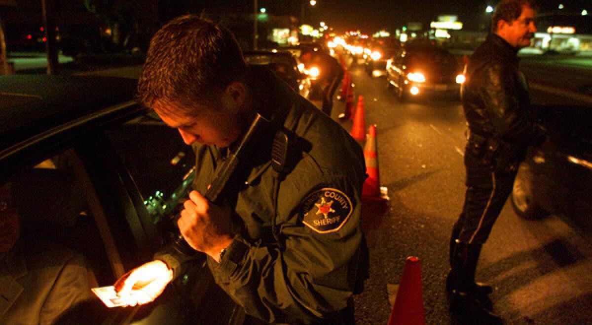 Orange County sheriff's Deputy Jeff Puckett, left, checks a motorist's identification at a DUI checkpoint.