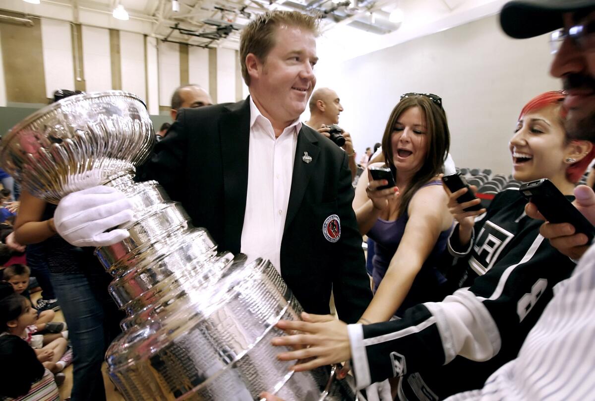 As Keeper of the Cup Mike Bolt carries the Stanley Cup, left, Jessica Brunstetter, 27 of Studio City, center, and Anita Papazian, 25 of Pasadena, right, get a brief touch of National Hockey League's Championship trophy during visit to Pacific Community Center and Park Gymnasium in Glendale on Wednesday, June 27, 2012. Hundreds showed up to get a close view of the trophy.