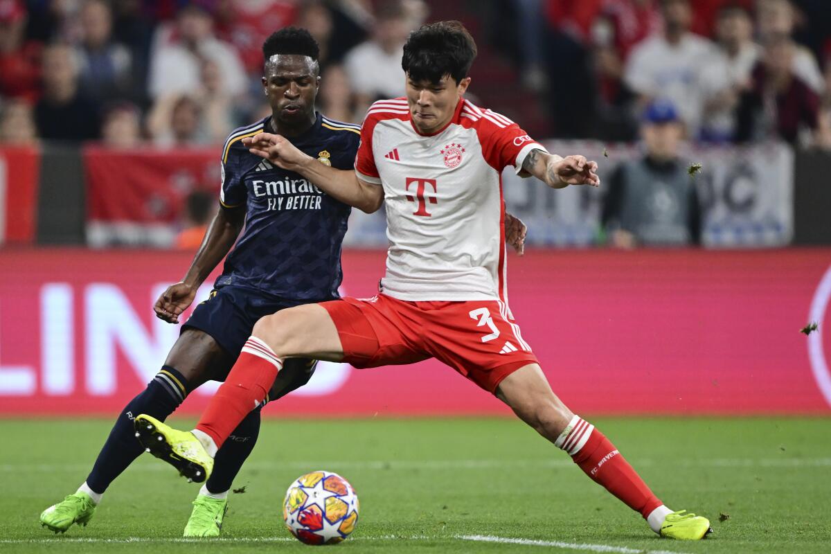 Kim Min-Jae del Bayern de Múnich (derecha) disputa el balón ante el brasileo del Real Madrid Vinicius 