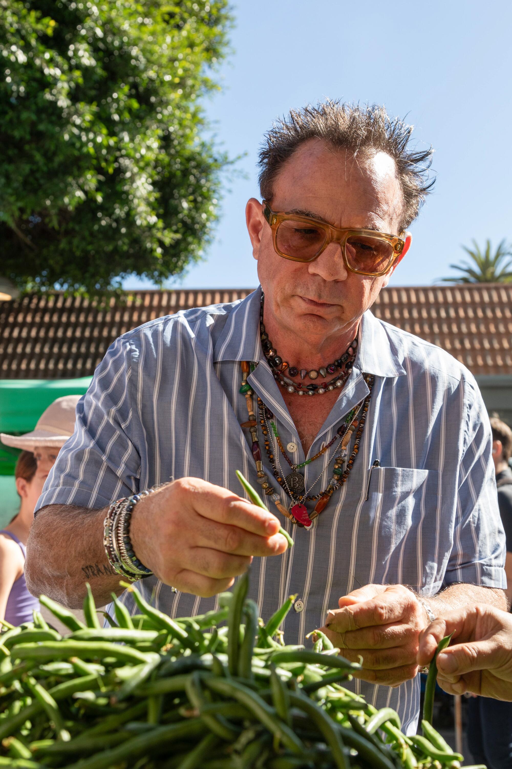 Chef Josiah Citrin picks through a pile of green beans at an outdoor farmers market