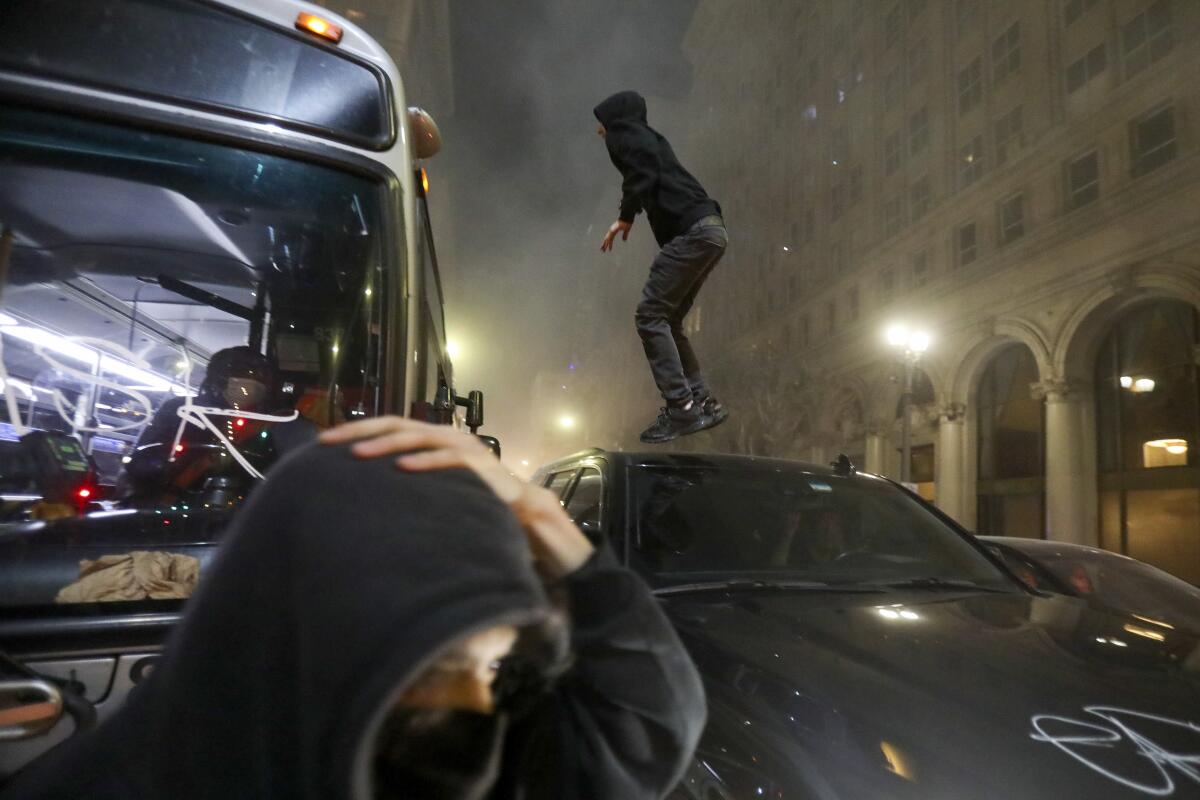 A man jumps on top of a vehicle as football fans celebrate the Los Angels Rams' Super Bowl win.