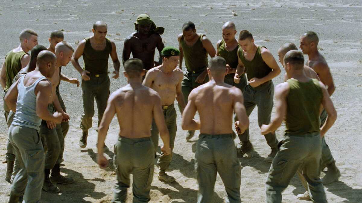 Shirtless soldiers run and play at the beach.