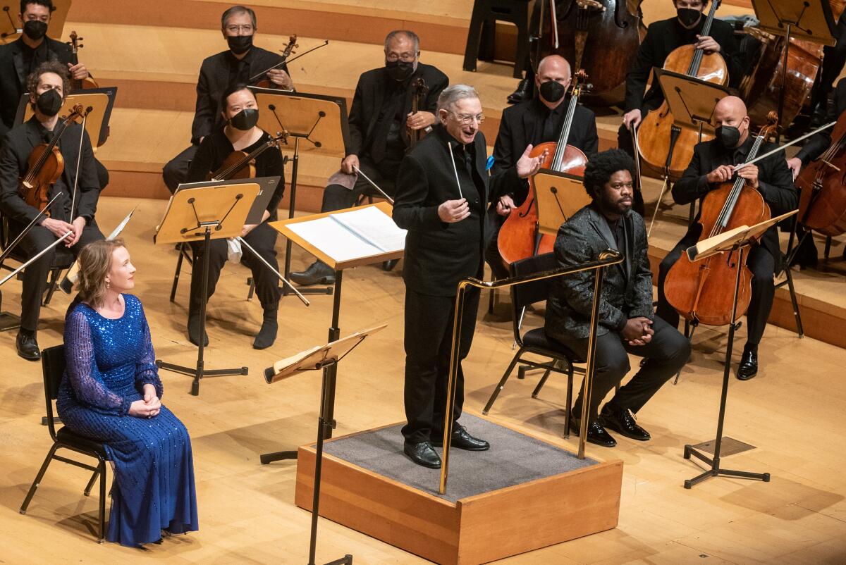 Michael Tilson Thomas stands on a podium — with soloists Sasha Cooke and Dashon Burton seated on either side of him.