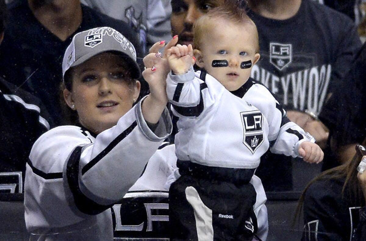 A fan holds has her baby knocks on the glass during a playoff game between the Kings and Sharks at Staples Center.