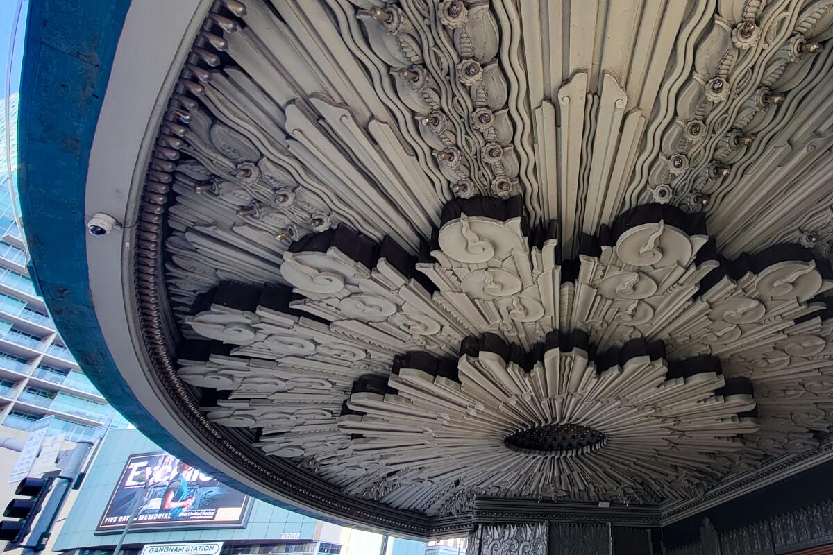 An entry canopy's ceiling is decorated with a huge medallion that looks like a blooming flower. 